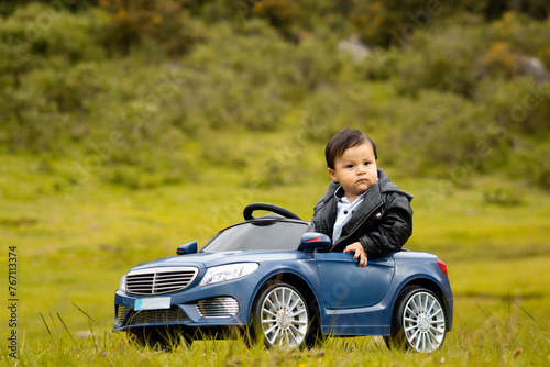 un niño jugando con un gran coche de juguete en el jardín de verano, al aire libre. niño conduciendo un coche . niño riéndose y sonriendo. el concepto de familia, aventuras saludables en mi vehículo