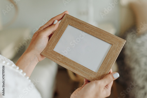 hands of bride in wedding dress hold photo frame