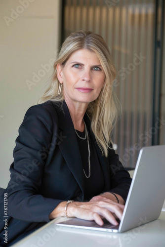 Middle aged business woman executive, female lawyer sitting at desk using laptop. Busy professional businesswoman manager working on computer corporate technology in modern office. Portrait.