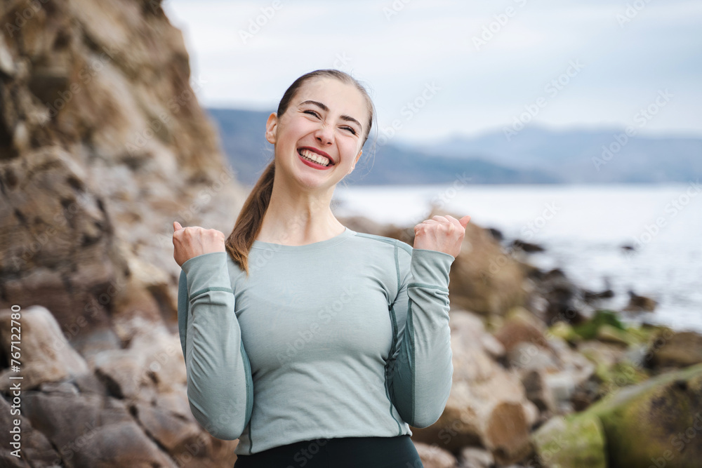 Young woman in sporty wear win competition raising fists celebrating cool achievement, cheerful positive girl all possible yelling voice raised fists in delight emotional high spirits mood
