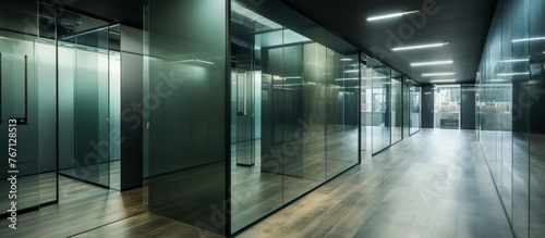 A long hallway in an office building with glass walls and wooden floors, showcasing the use of composite materials and transparent tints