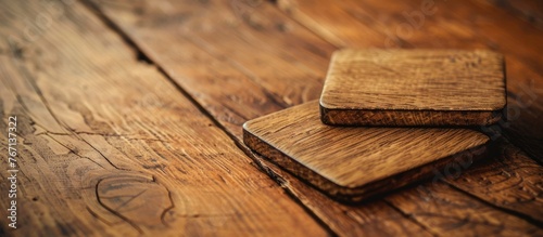 Two empty square beer coasters on a wooden table surface. photo