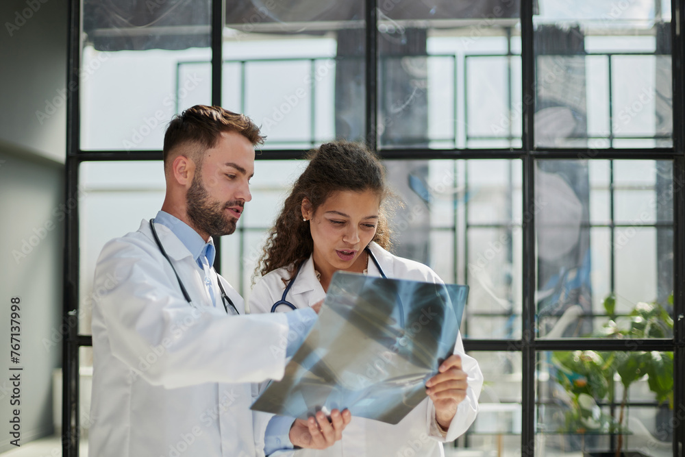 Young serious competent male doctor looking at X-ray at doctor's office Young serious competent male doctor looking at X-ray at doctor's office