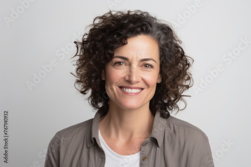 Portrait of a smiling middle-aged woman with curly hair on a gray background