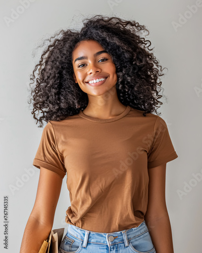 Portrait of a smiling young woman holding shopping bags against grey background