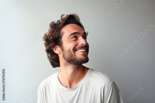 Portrait of a happy young man laughing against a gray background. © Loli