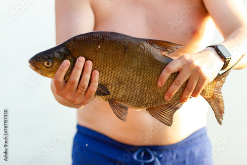 Fototapeta Naklejka Na Ścianę i Meble -  The man caught a large bream, holds it in his hands