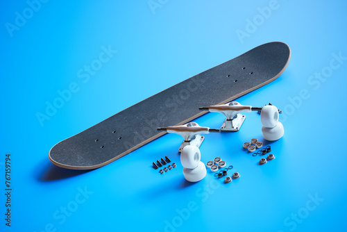 Disassembled Black Skateboard and Components on Bright Blue Surface
