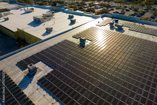 Production of sustainable energy. Aerial view of solar power plant with blue photovoltaic panels mounted on industrial building roof for producing green ecological electricity