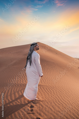 Arab man stands alone in the desert and watching the sunset.