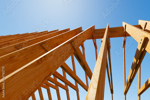 Unfinished Wooden House Frame Under a Clear Blue Sky: Construction Process photo