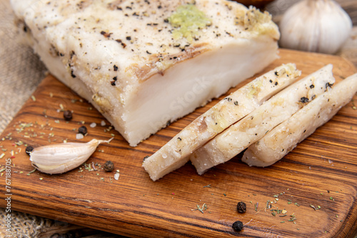 Lard with garlic on wooden board. Sliced salted salo closeup