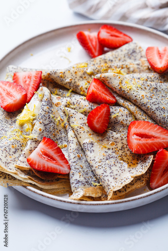 Crepes with poppy seeds, maple syrup and strawberries. photo