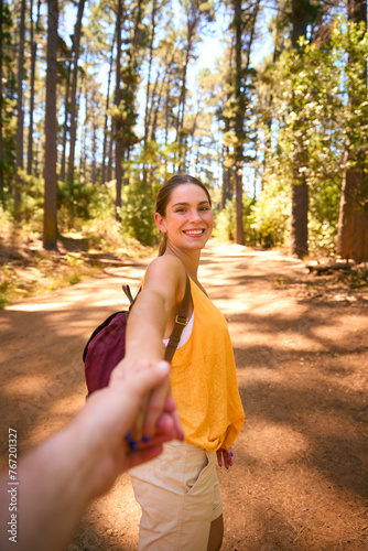 POV Shot Of Loving Couple Wearing Backpacks Holding Hands Hiking Along Trail Through Countryside