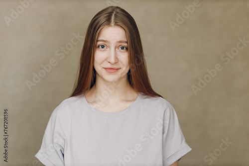 Portrait of young pretty smiling woman looking at camera against beige background