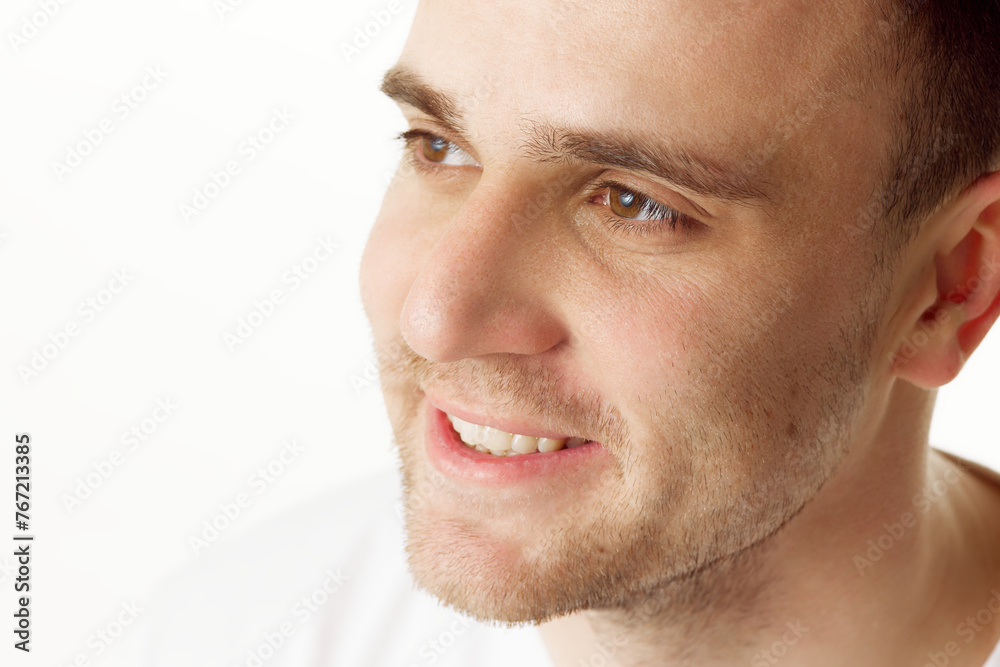 Close up portrait of smiling man with short hair and stubble, looking to side against white studio background. Concept of natural beauty, spa treatments, masculine, cosmetology.