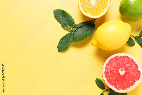 Different cut and whole citrus fruits on yellow table, flat lay. Space for text