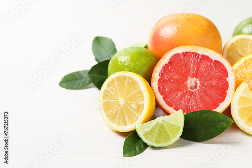 Different cut and whole citrus fruits on white wooden table, closeup. Space for text