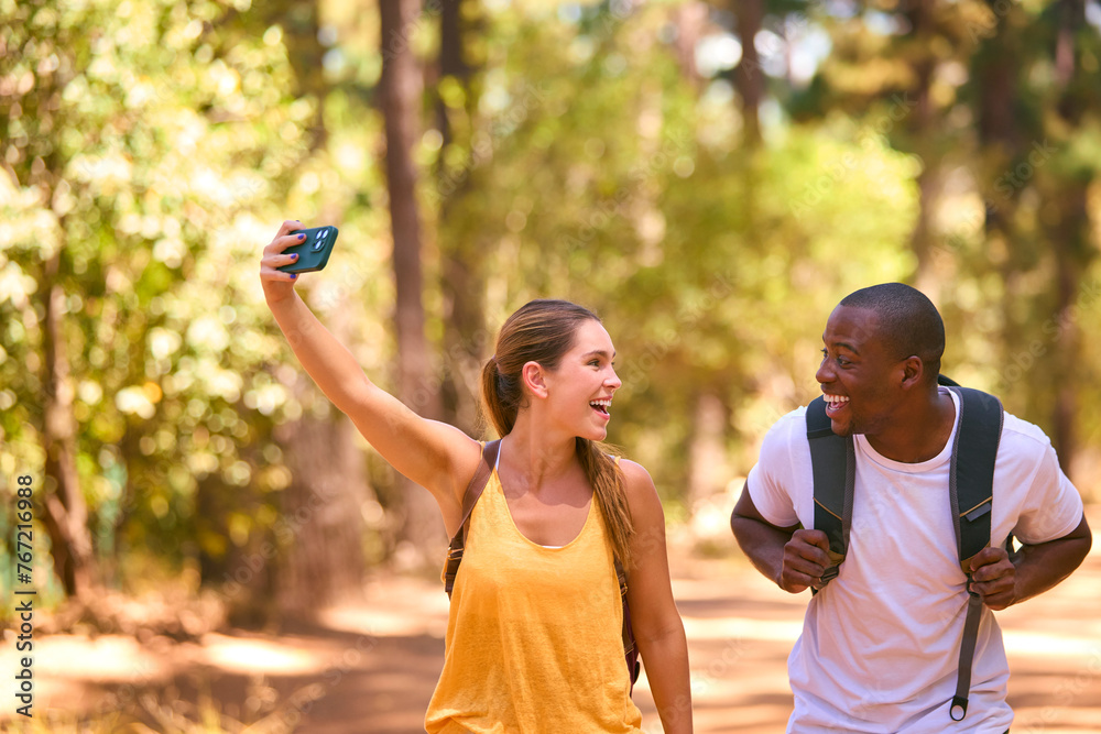 Couple Hiking Along Trail In Countryside Posing For Selfie Or Filming Video On Mobile Phone