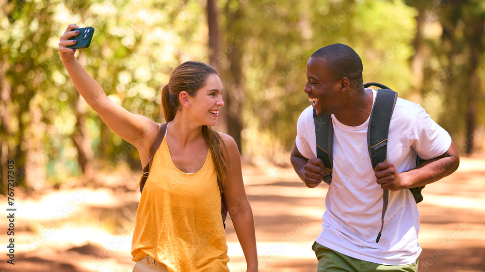 Obraz premium Couple Hiking Along Trail In Countryside Posing For Selfie Or Filming Video On Mobile Phone