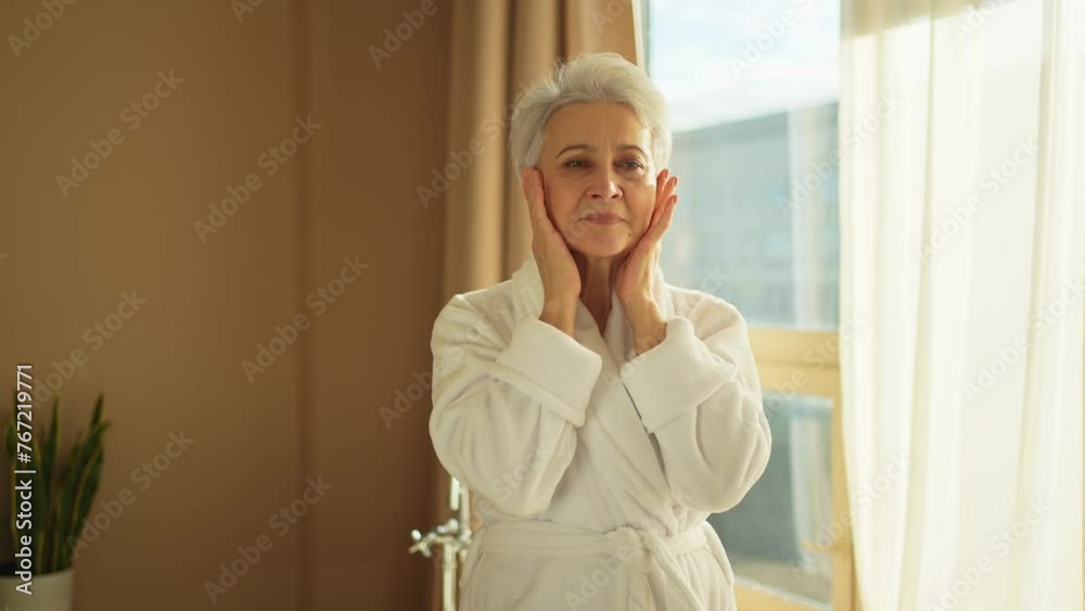 Mature adult old woman applying nourishing anti age face cream doing daily beauty routine. Senior woman touching face skin wrinkles gets facial treatment. Skin care aging beauty skincare cosmetics Mature adult old woman applying nourishing anti age face cream doing daily beauty routine. Senior woman touching face skin wrinkles gets facial treatment. Skin care aging beauty skincare cosmetics
