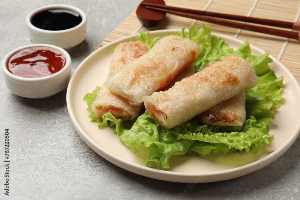 Delicious fried spring rolls served on grey table