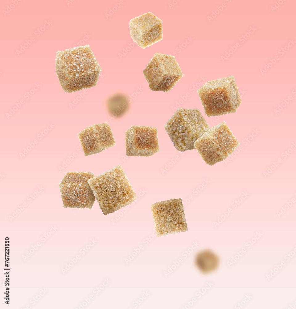 Brown cane sugar cubes falling on pink gradient background Brown cane sugar cubes falling on pink gradient background