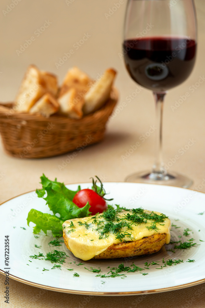Baked potatoes with cheese and herbs on a plate and with red wine Baked potatoes with cheese and herbs on a plate and with red wine