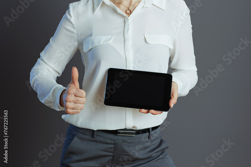 Modern business owner woman showing tablet PC and thumbs up