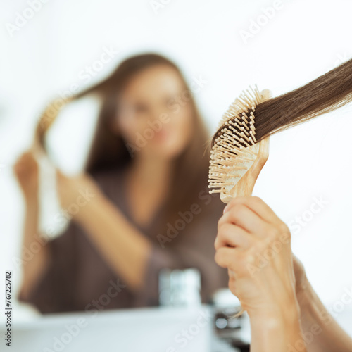 Young woman combing hair in bathroom. rear view
