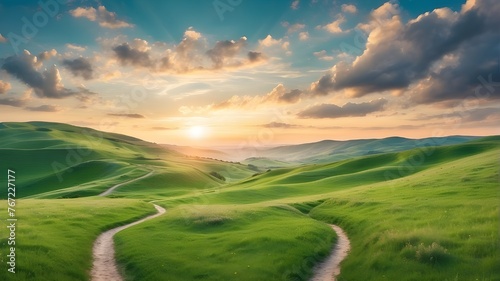 Beautiful winding path in the morning at dawn, with clouds and a beautiful sky, through a green grass field in a hilly terrain. A naturally occurring, expansive spring or summer scene