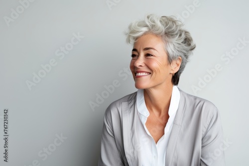 Portrait of a happy senior businesswoman smiling while standing against grey background