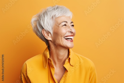 Cheerful senior woman. Portrait of cheerful mature woman looking away and smiling while standing against yellow background