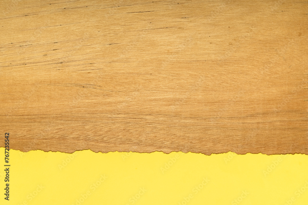 Piece of yellow torn paper on a wooden background. Space for text.