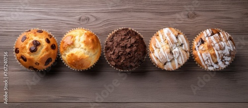 Four muffins with chocolate frosting on a wooden table