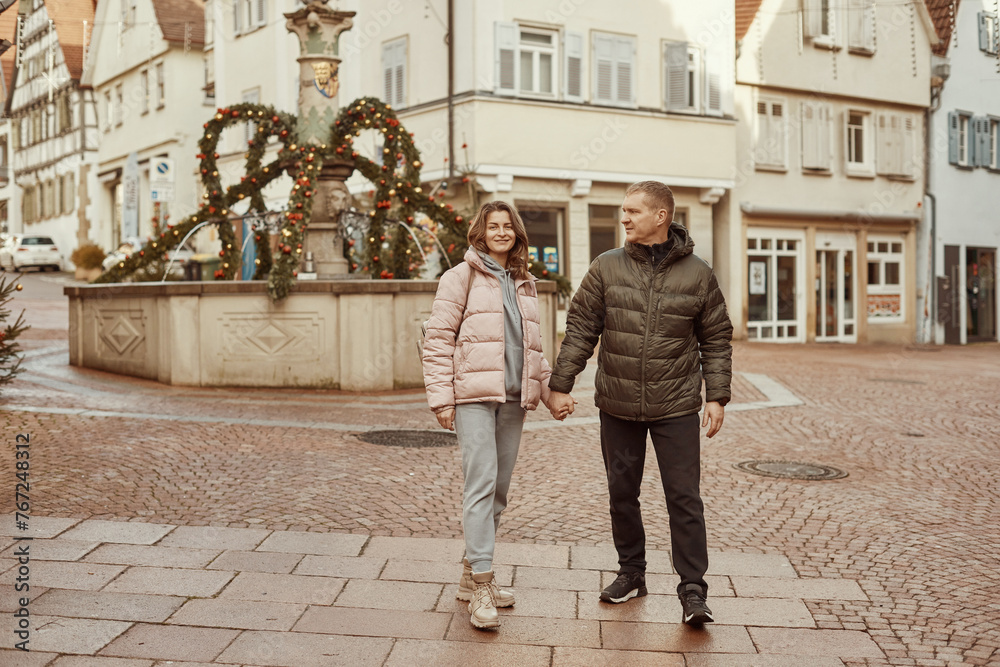 Obraz premium Loving couple of tourists walking around old town. Couple of lovers leisurely stroll in the cool autumn morning on the streets of a BIETIGHEIM-BISSINGEN (Germany). The guy holds his wife. Vacation