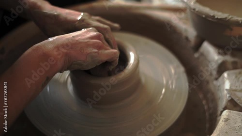 An Argentinean ceramist delicately smooths the interior of a clay vessel with a moist sponge, perfecting its shape on the pottery wheel photo