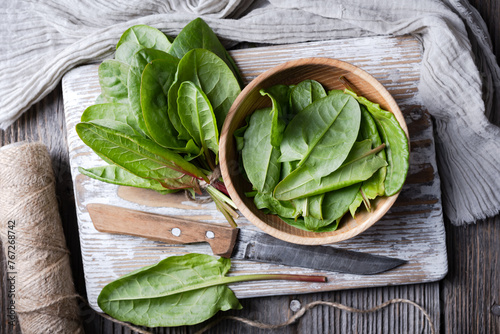 Top view on fresh organic sorrel leaves in wooden bowl with knife close up. Food photography