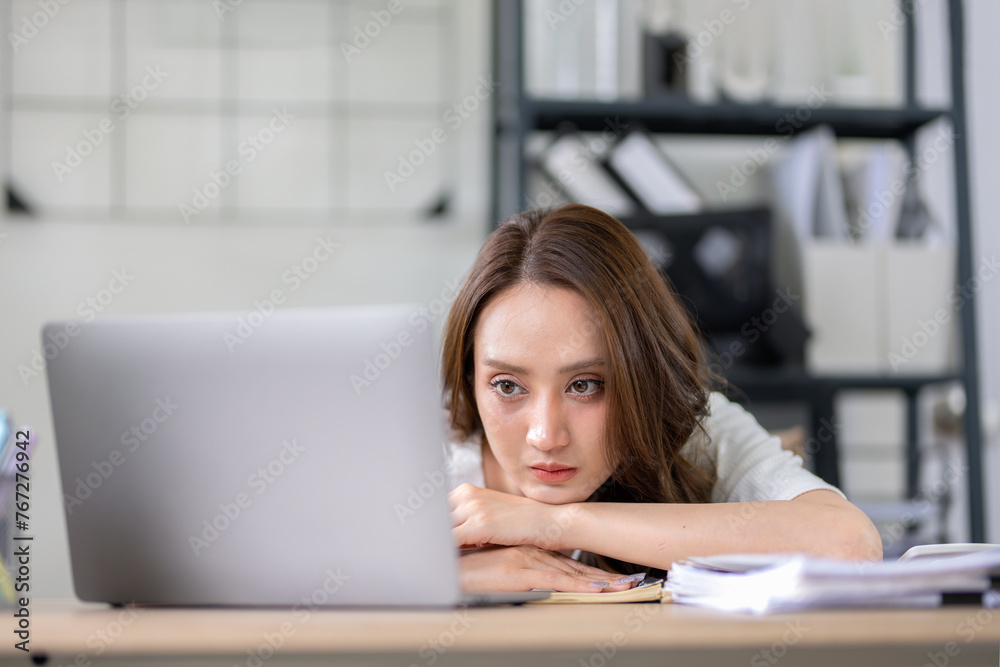 Businesswoman looks stressed, bored and holding her head. Indicates a headache while working at a desk in home office. Businesswoman looks stressed, bored and holding her head. Indicates a headache while working at a desk in home office.