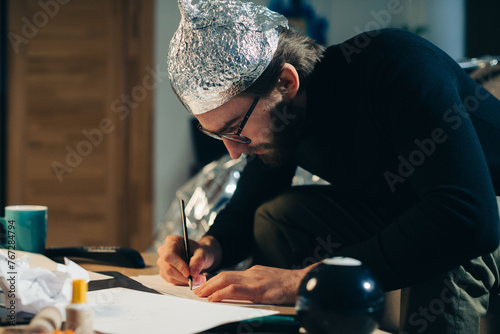 Unveiling Conspiracies: Man in Foil Hat Crafting Cryptic Signs