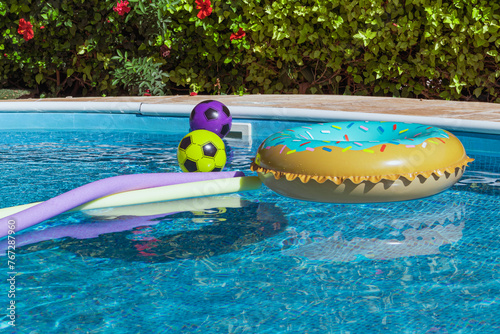 Yellow pool float, pool inflatable ring and balls float in the pool. Swimming pool safety © Armands photography