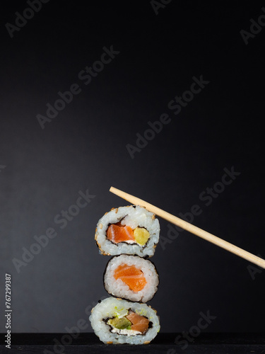 sushi preparado sobre hojas plato y pizarra con fondo negro