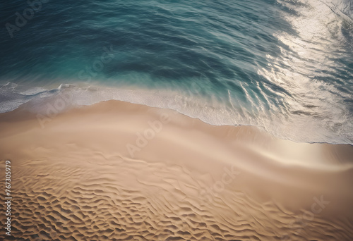 Aerial view of gentle waves washing onto a sandy beach, with a clear demarcation between sea and shore. photo