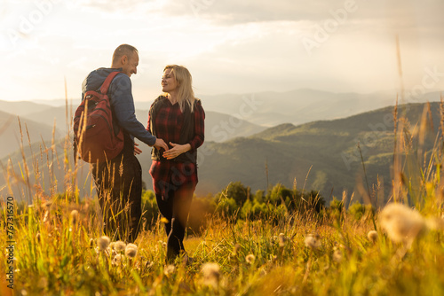 A man and a woman in tourist equipment are standing on a rock and admiring the panoramic view. A couple in love on a rock admires the beautiful views. A couple in love is traveling. A couple on a hike photo
