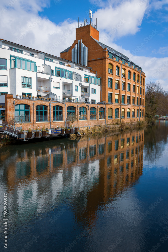 Obraz premium weißes und rotes Gebäude mit Spiegelung im Wasser an der weißen Elster in Leipzig