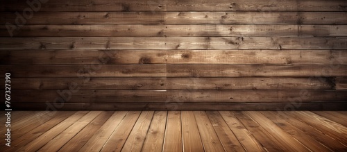A brown hardwood flooring made of wooden planks extends in front of a wooden wall, displaying various tints and shades of wood stain in a beautiful pattern