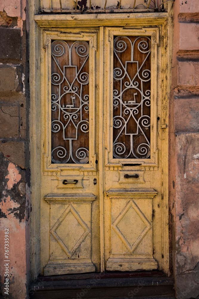 Pale, painted, yellow doors on a pink stone, abandoned building in Old Town, Tbilisi, Georgia. Pale, painted, yellow doors on a pink stone, abandoned building in Old Town, Tbilisi, Georgia.