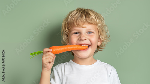 Portrait of a little boy with a carrot on a green background. The child eats carrots.