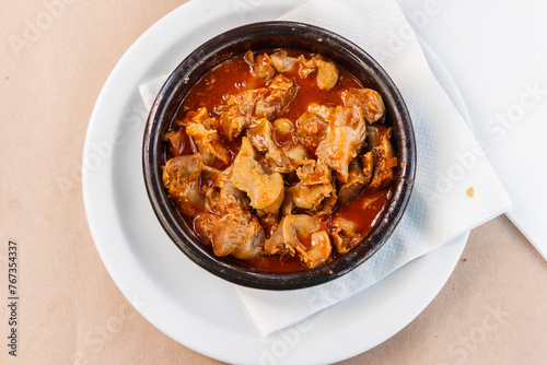 Stewed chicken gizzards in a sauce in a bowl on the table. Top view. Typical Spanish appetizer