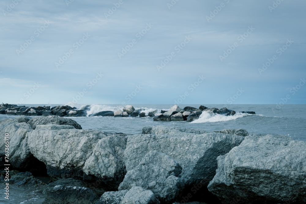 Riviera Romagnola scenic view, winter sea, rock reef, metallic and dramatic sky, stormy weather.